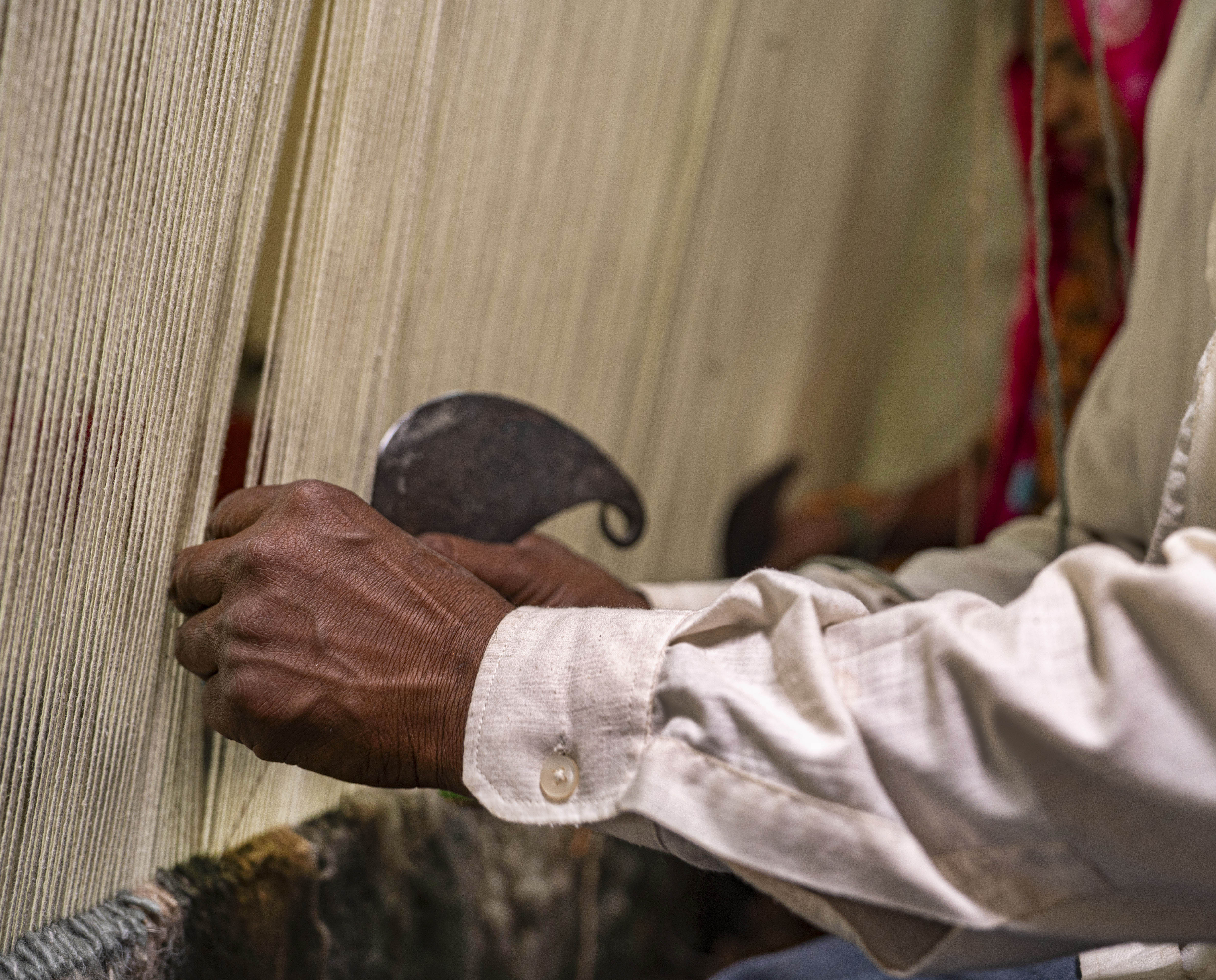 Handmade carpet manufacturing process showing an artisan weaving a premium wool rug