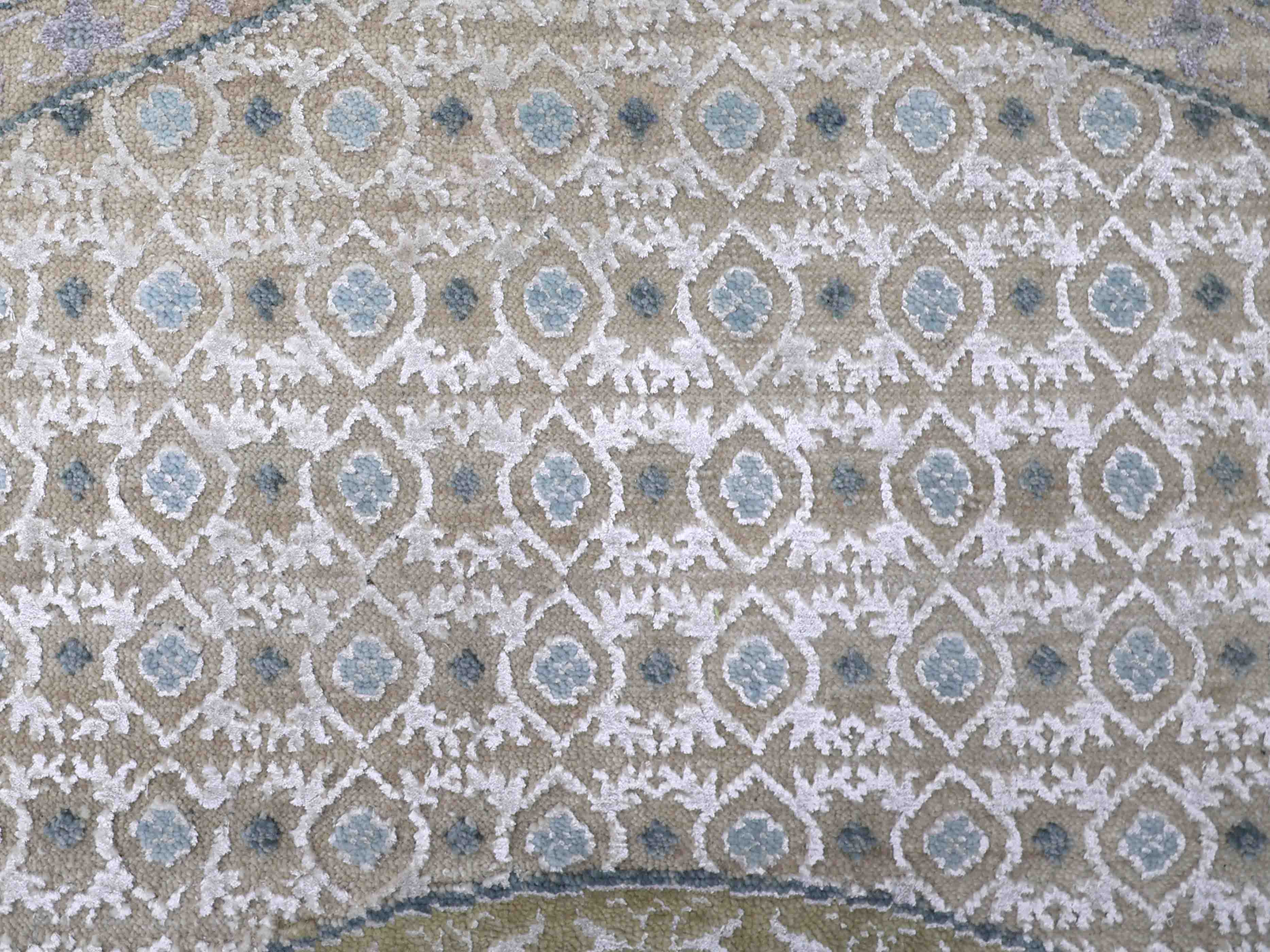 Ornate rug pattern with repeating diamond shapes featuring blue floral centers on a beige background. The design feels elegant and classic.