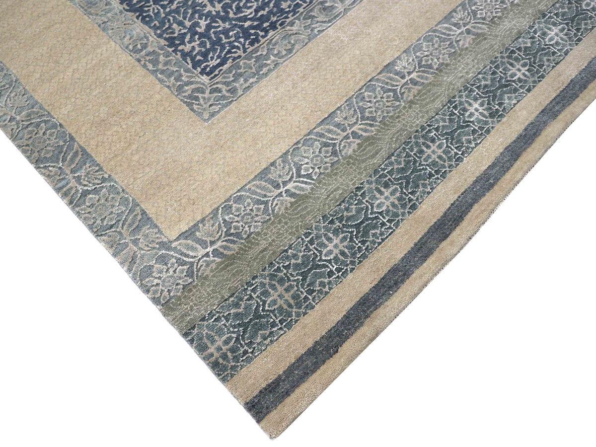 Corner of a decorative rug featuring a beige and blue color scheme with intricate floral patterns and geometric borders, evoking elegance and warmth.