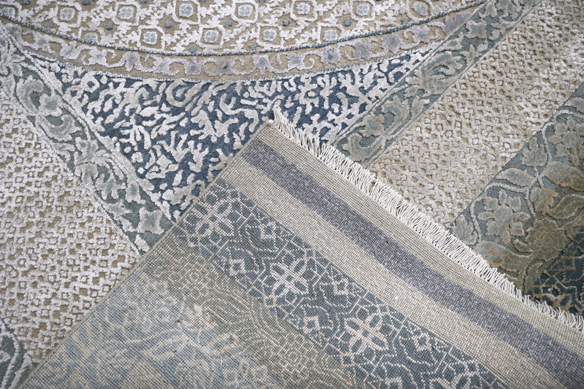 A close-up of overlapping rugs with intricate patterns in muted blues, grays, and creams. The detail showcases floral and geometric designs.