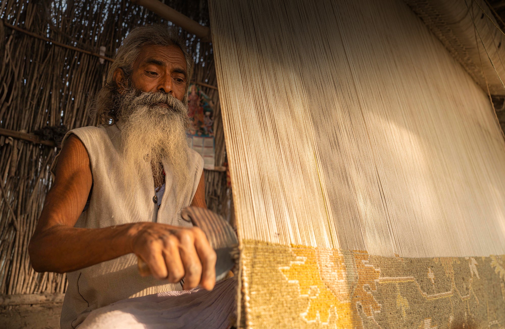 Artisan weaving a handmade carpet on a loom with intricate patterns and natural light