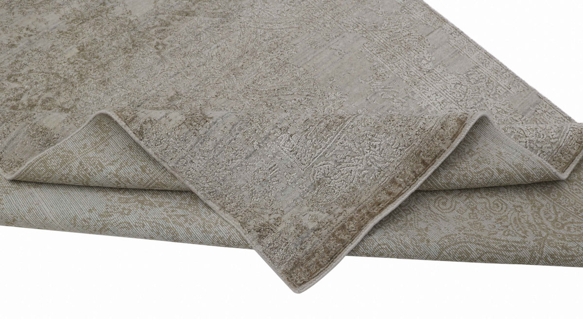 Close-up of a folded beige handmade carpet with an intricate vintage floral pattern