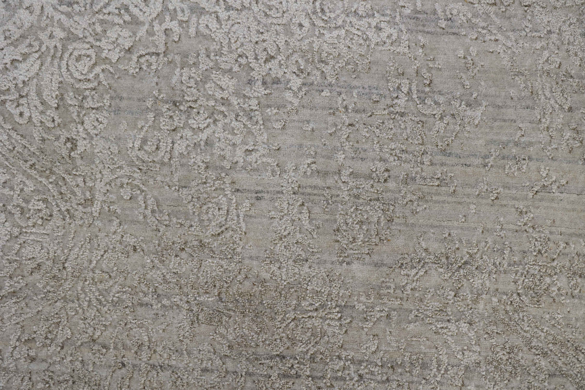 Close-up of a neutral beige handmade rug with a textured embossed floral pattern