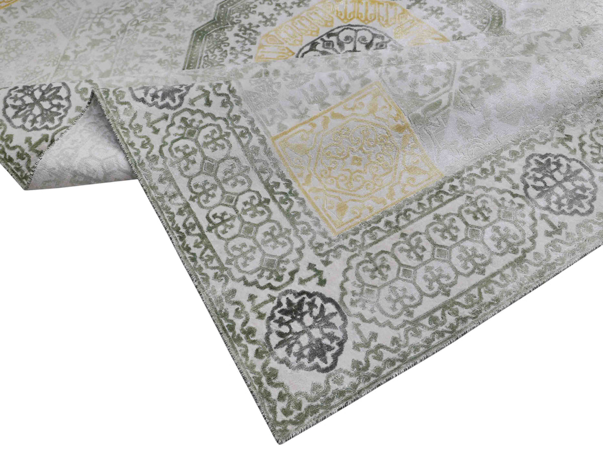 A fabric with an intricate pattern featuring interwoven geometric shapes and floral motifs in green, gray, and yellow tones. The design is ornate and elegant.