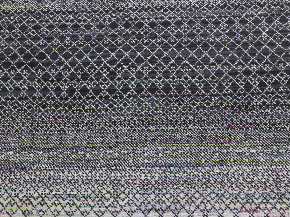 A textured surface with a geometric pattern of white diamonds on a black background, gradually transitioning to a mix of colors, creating a dynamic visual effect.
