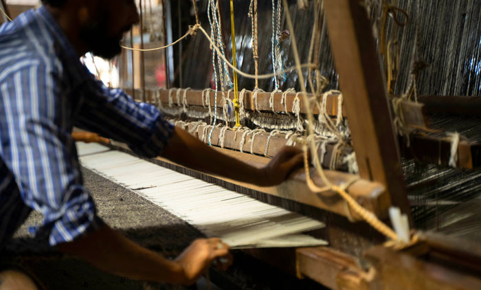 Artisan weaving a handmade carpet on a traditional loom, close-up of hands and threads